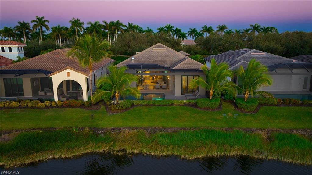 18488 Miromar Lakes Boulevard Miromar Lakes, FL 33913 - Photo 33 of 48 a front view of a house with a garden and a yard