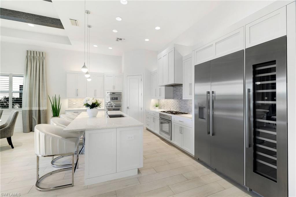 18488 Miromar Lakes Boulevard Miromar Lakes, FL 33913 - Photo 9 of 48 a kitchen with stainless steel appliances kitchen island granite countertop a refrigerator and a stove top oven