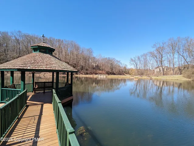 a roof deck with table and chairs under an umbrella with wooden floor and fence