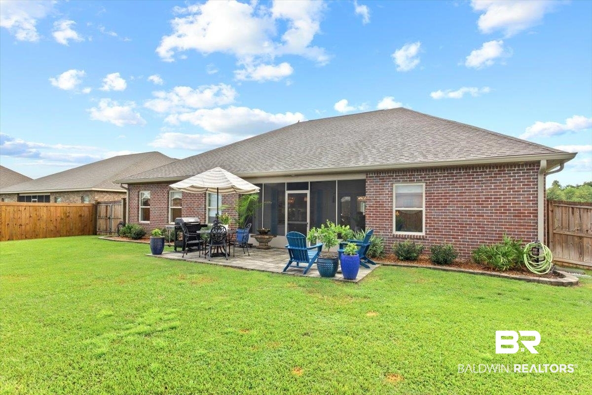 7056 Rocky Rd Loop Gulf Shores, AL 36542 - Photo 35 of 41 Back of property featuring a fenced backyard, a sunroom, brick siding, a patio, and a shingled roof