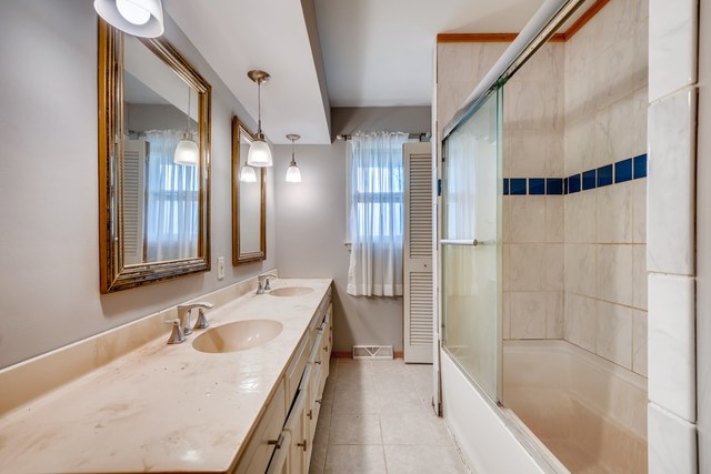 1331 West Maple Road New Lenox, IL 60451 - Photo 10 of 17 a bathroom with a granite countertop sink a mirror and shower
