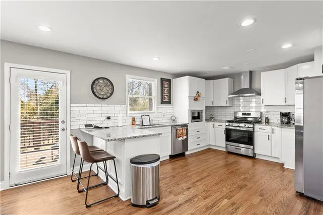 a kitchen with stainless steel appliances granite countertop white cabinets a stove a sink and a potted plant