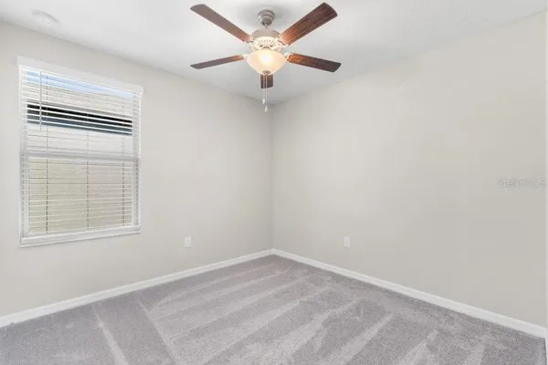 an empty room with a window and a fan