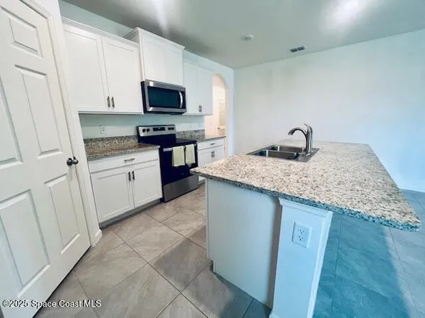 a kitchen with granite countertop a sink and a stove top oven with wooden floor