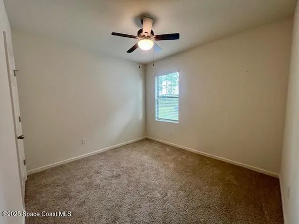 an empty room with a window and a ceiling fan