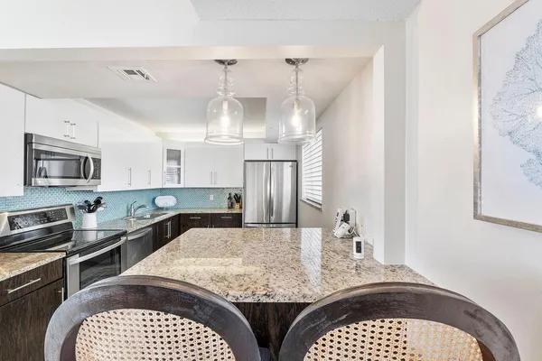 a kitchen with granite countertop white cabinets and stainless steel appliances