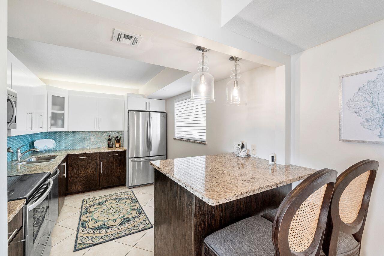 100 Ocean Trail Way, Unit 207 Jupiter, FL 33477 - Photo 13 of 61 a kitchen with granite countertop a table chairs stove and refrigerator