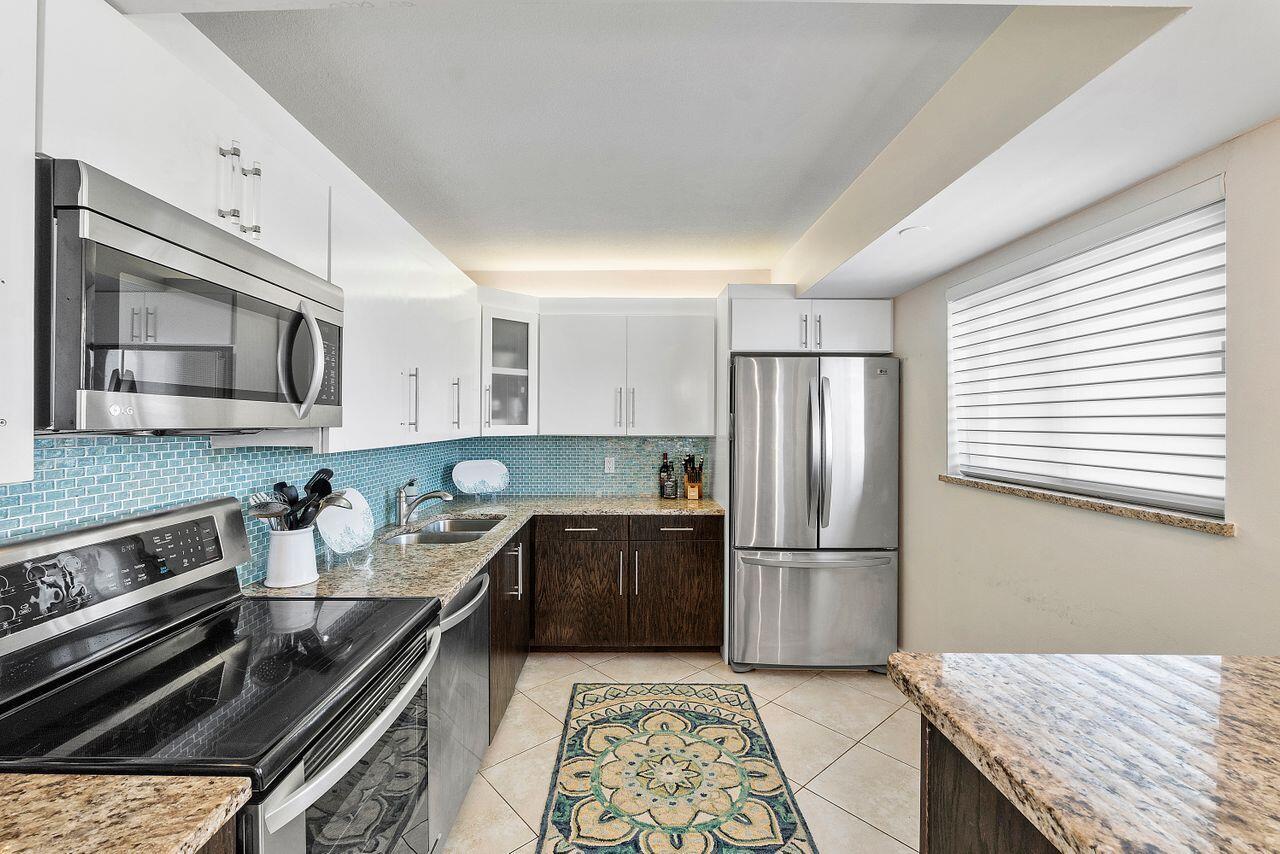 100 Ocean Trail Way, Unit 207 Jupiter, FL 33477 - Photo 14 of 61 a kitchen with granite countertop stainless steel appliances and wooden cabinets