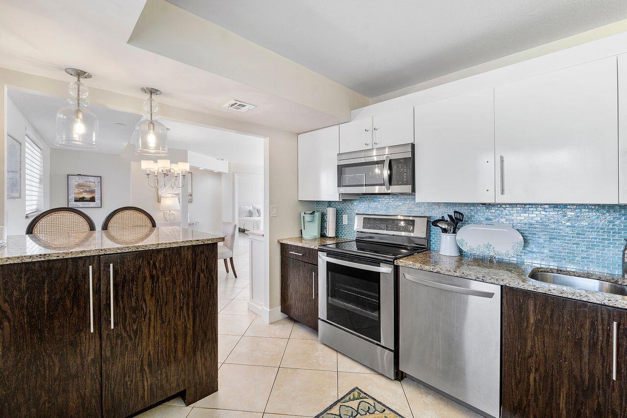 100 Ocean Trail Way, Unit 207 Jupiter, FL 33477 - Photo 15 of 61 a kitchen with granite countertop white cabinets and stainless steel appliances