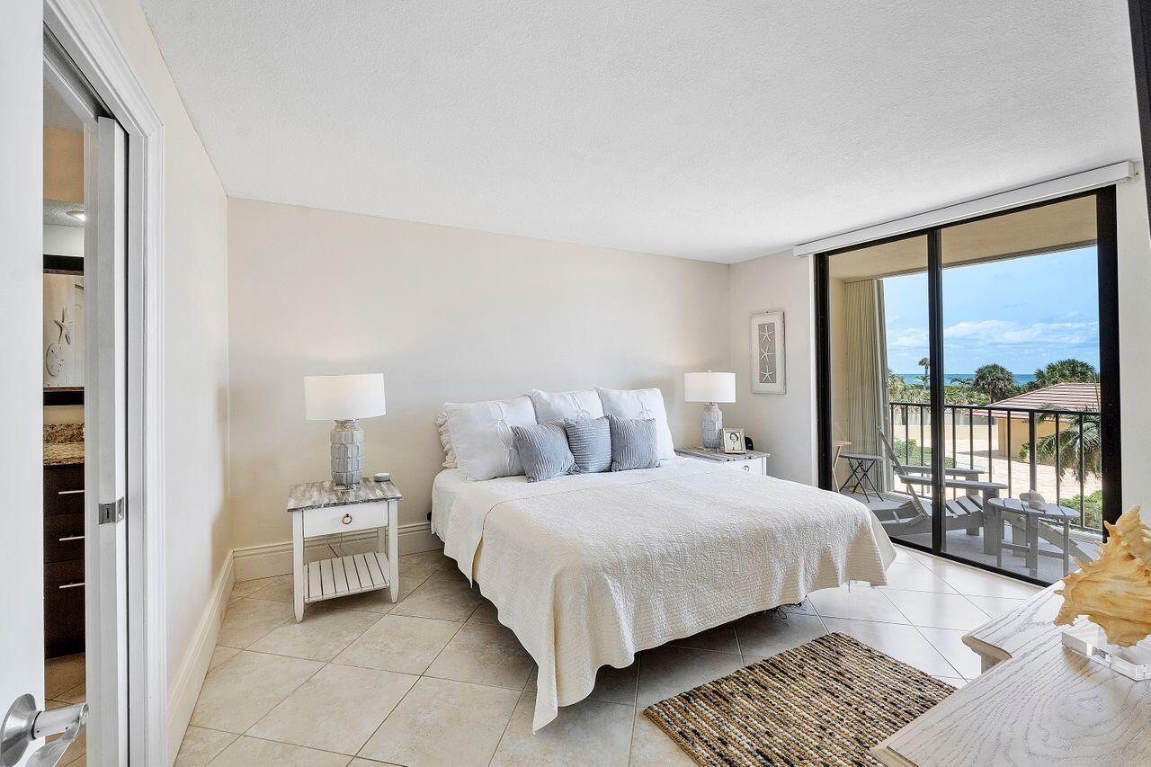 100 Ocean Trail Way, Unit 207 Jupiter, FL 33477 - Photo 17 of 61 a bedroom with a bed lamp and a large window