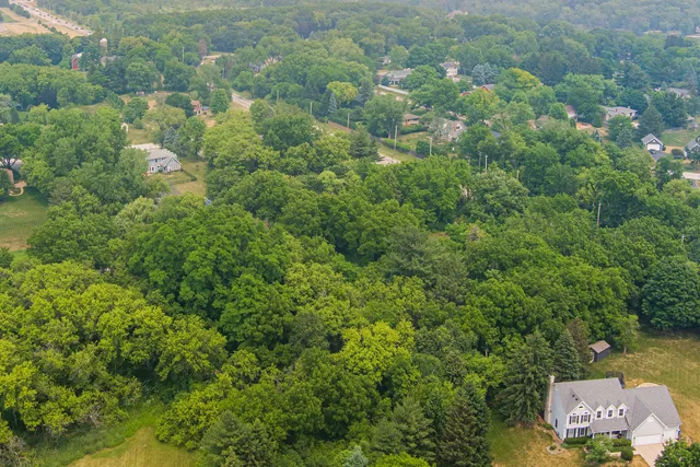 an aerial view of residential house with outdoor space and trees all around