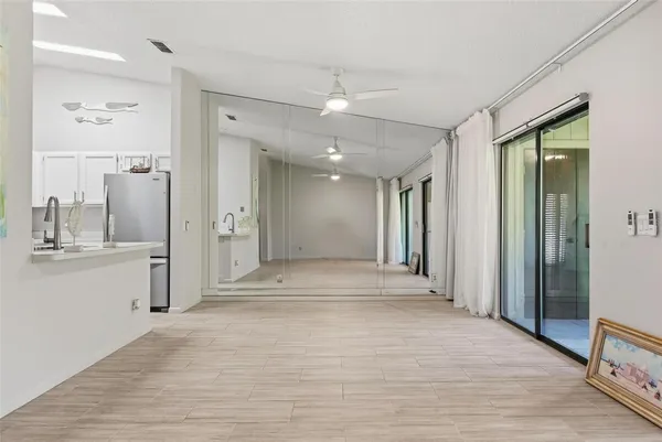 a view of an empty room with kitchen and a window