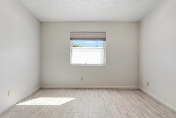 an empty room with wooden floor closet and windows