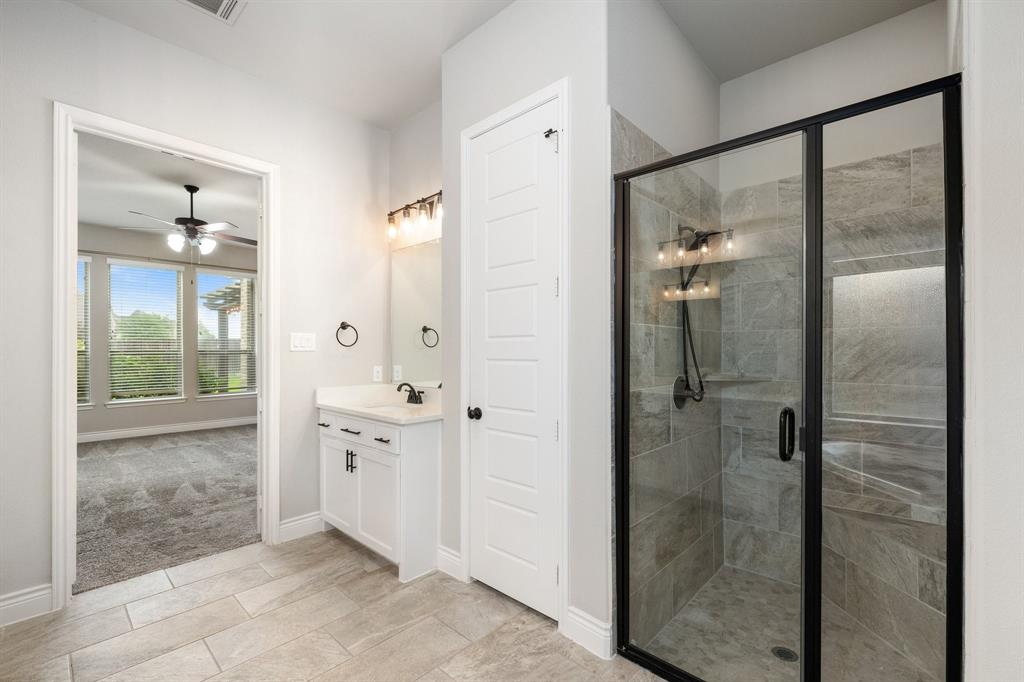 1501 Calcot Lane Forney, TX 75126 - Photo 18 of 34 Contemporary bathroom featuring a frameless glass shower enclosure with matte black accents, tile surround, and built-in shelving