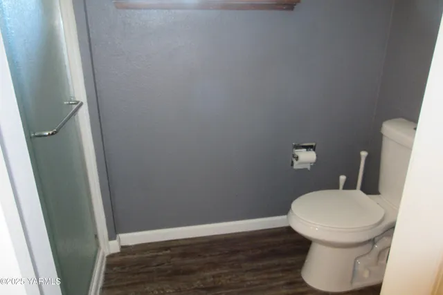 a white toilet sitting next to a wooden floor