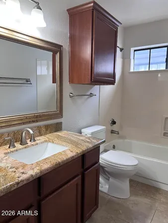a bathroom with a granite countertop sink toilet and mirror