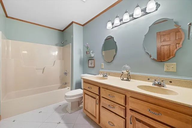 a spacious bathroom with a toilet a double vanity sink and a mirror