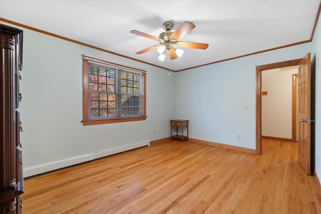 an empty room with wooden floor chandelier fan and windows