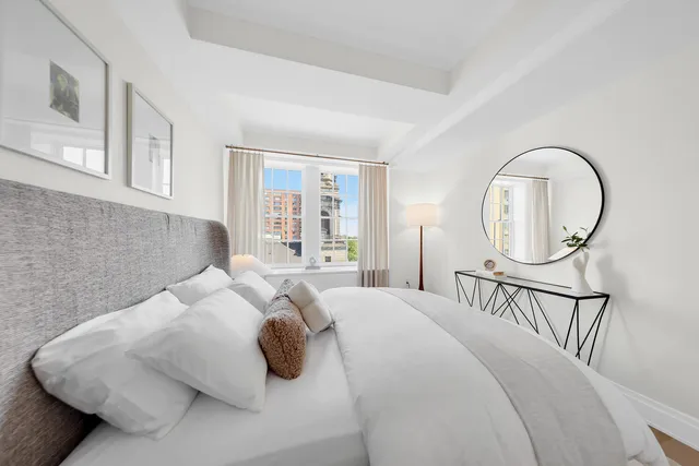 a bedroom with a bed a mirror and a large window