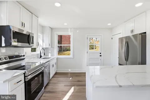 a large kitchen with stainless steel appliances granite countertop a stove a sink and a refrigerator