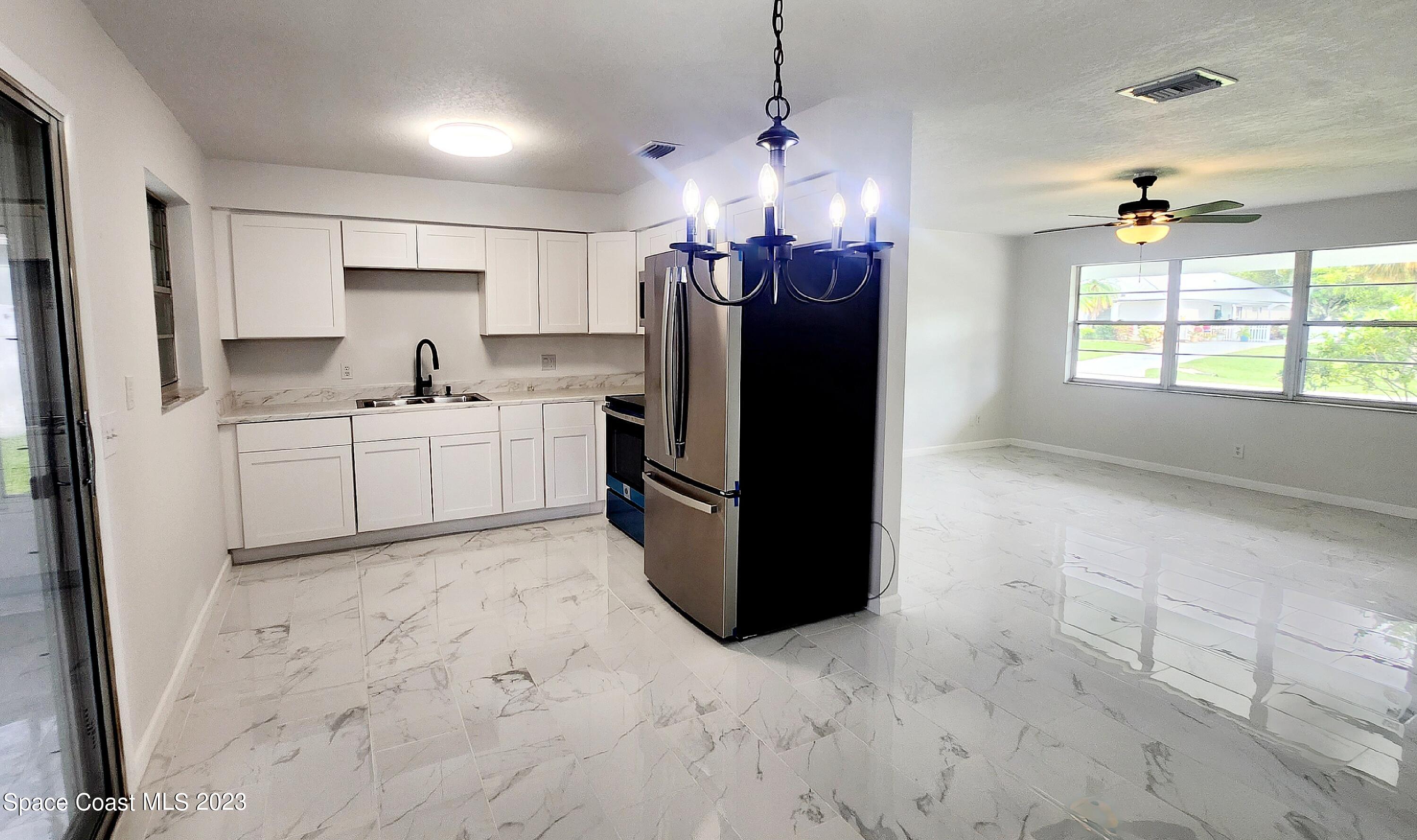 925 Gulfstream Avenue Sebastian, FL 32958 - Photo 19 of 19 a kitchen with stainless steel appliances granite countertop a refrigerator a sink a stove and white cabinets with wooden floor