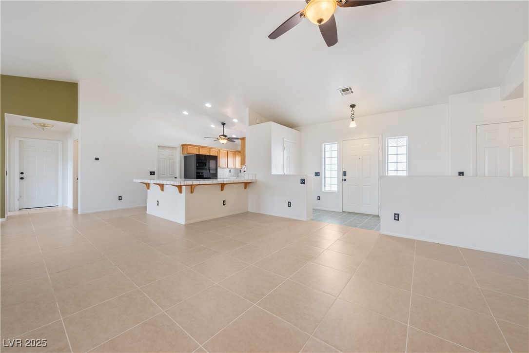 3581 Ranger Way Pahrump, NV 89048 - Photo 22 of 57 Unfurnished living room featuring light tile patterned floors, ceiling fan, visible vents, and vaulted ceiling