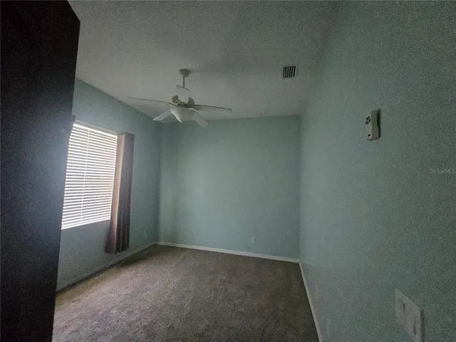 an empty room with windows and fan