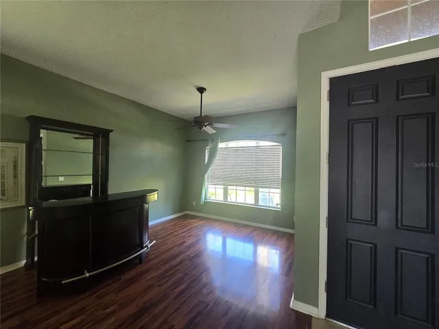 an empty room with wooden floor cabinet and windows