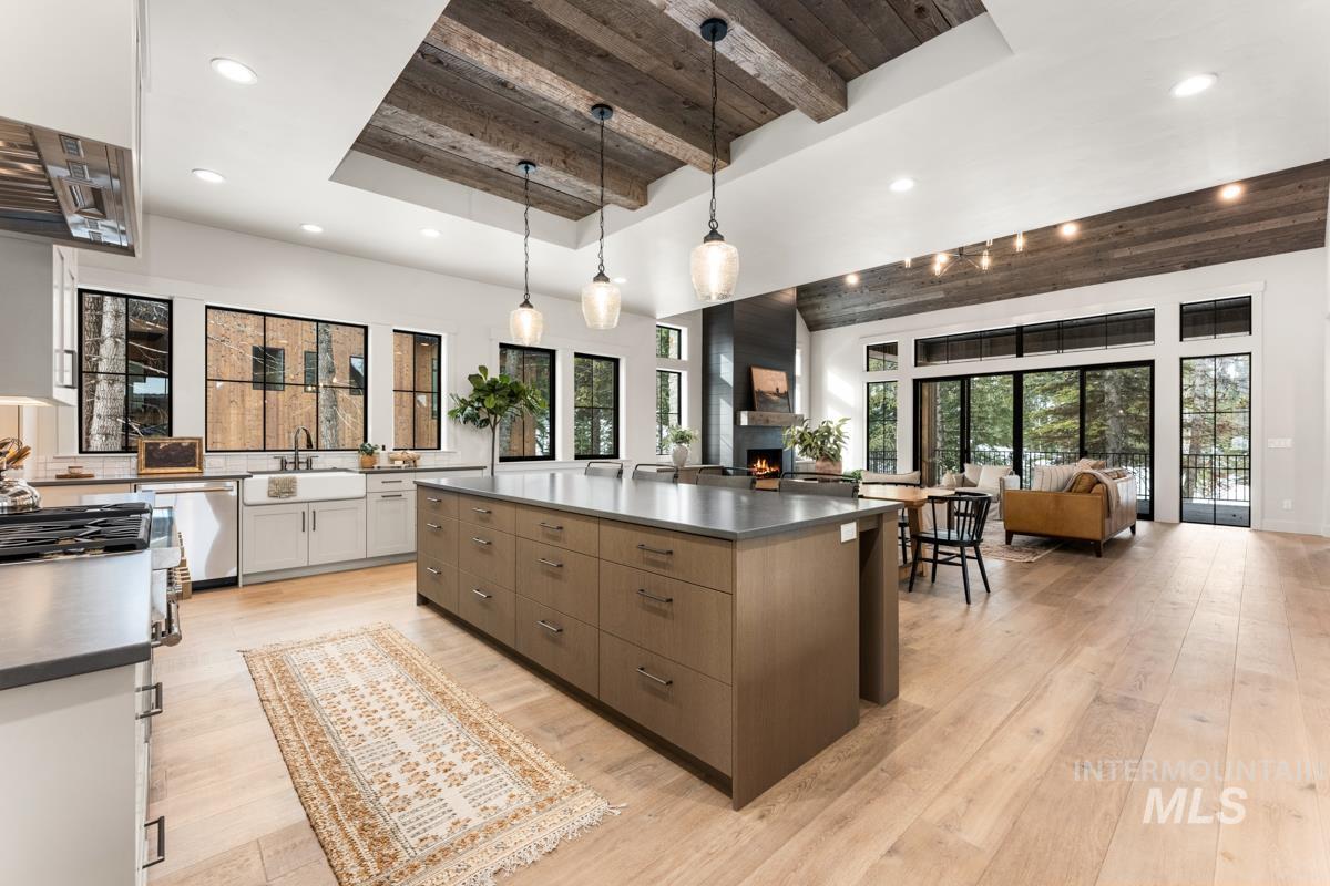 68 Ponderosa Ridge Donnelly, ID 83615 - Photo 15 of 29 Kitchen with a wooden tray ceiling, light wood-type flooring, a large island, decorative light fixtures, and a large fireplace