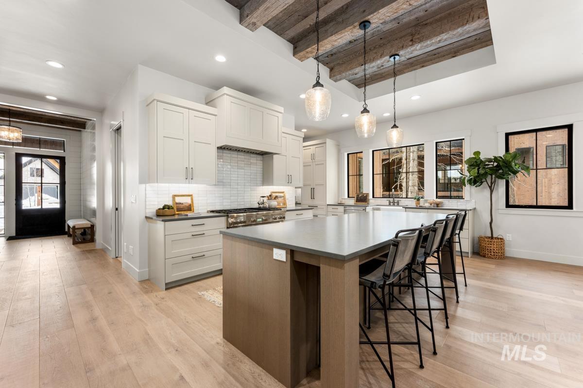 68 Ponderosa Ridge Donnelly, ID 83615 - Photo 16 of 29 Kitchen featuring a spacious island, two tone cabinets, a kitchen bar, hanging light fixtures, and dark countertops