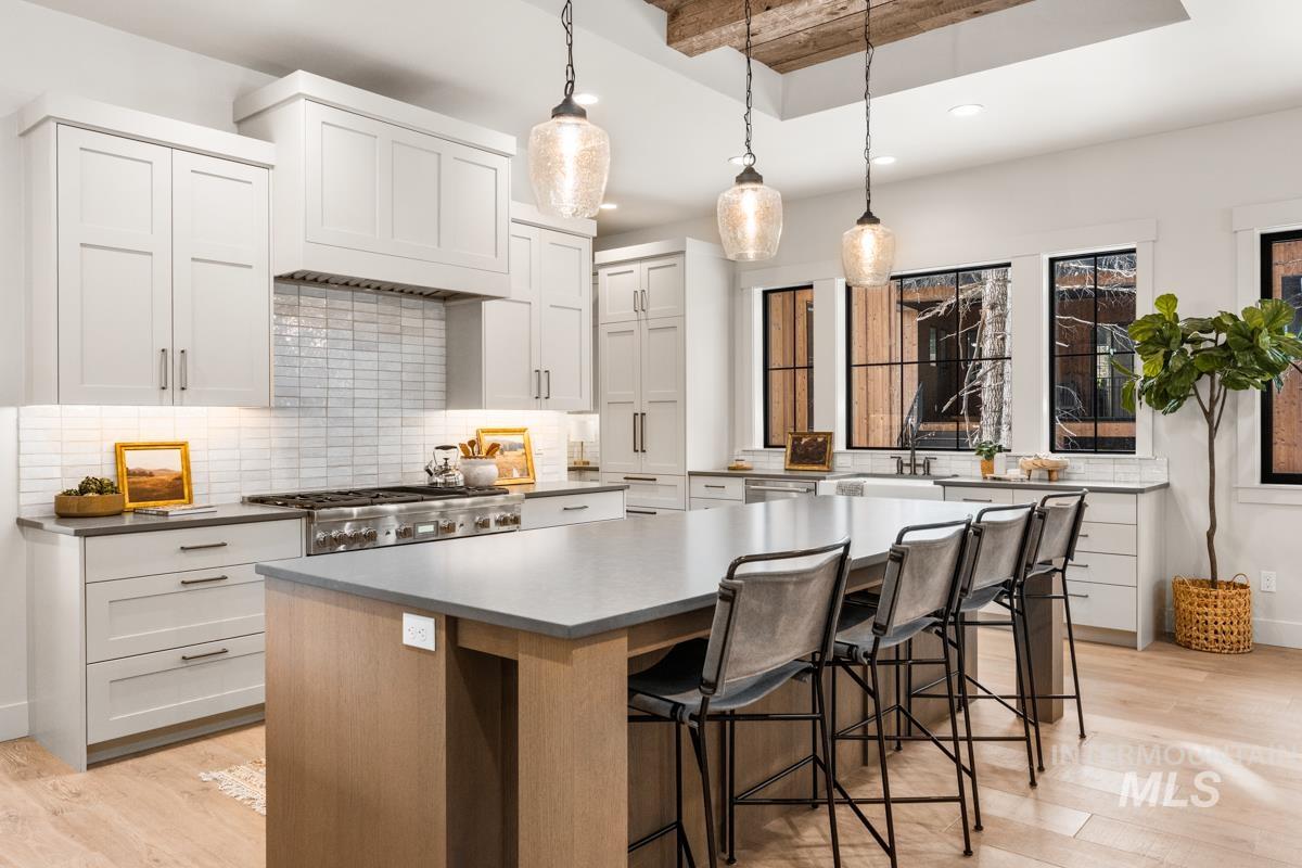 68 Ponderosa Ridge Donnelly, ID 83615 - Photo 17 of 29 Kitchen featuring a large island, a breakfast bar area, light wood-style floors, tasteful backsplash, and two tone cabinetry