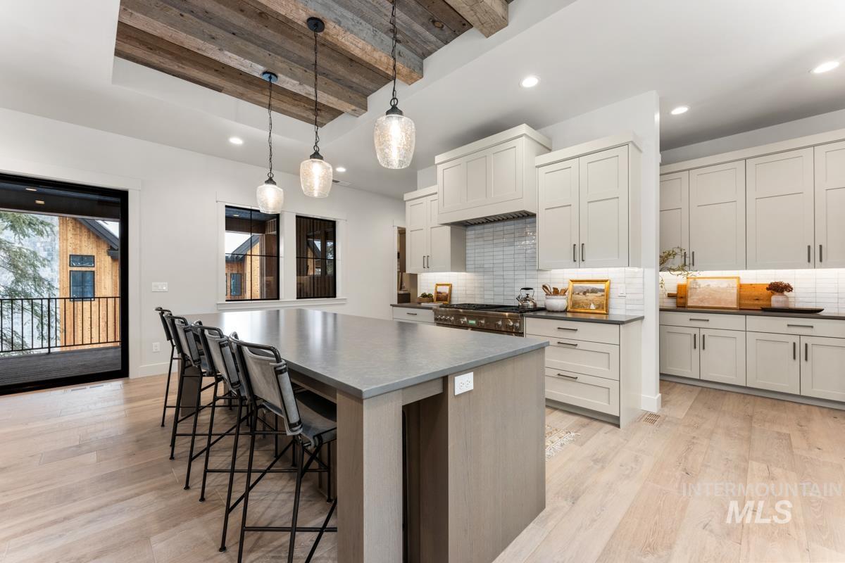68 Ponderosa Ridge Donnelly, ID 83615 - Photo 19 of 29 Kitchen featuring beam ceiling, a breakfast bar, a spacious island, light wood-style flooring, and decorative light fixtures