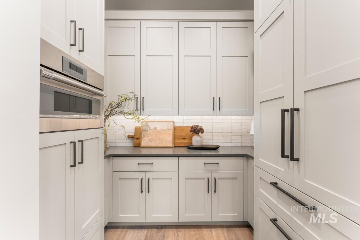 68 Ponderosa Ridge Donnelly, ID 83615 - Photo 24 of 29 Kitchen featuring stainless steel oven, white cabinetry, light wood-style floors, and decorative backsplash