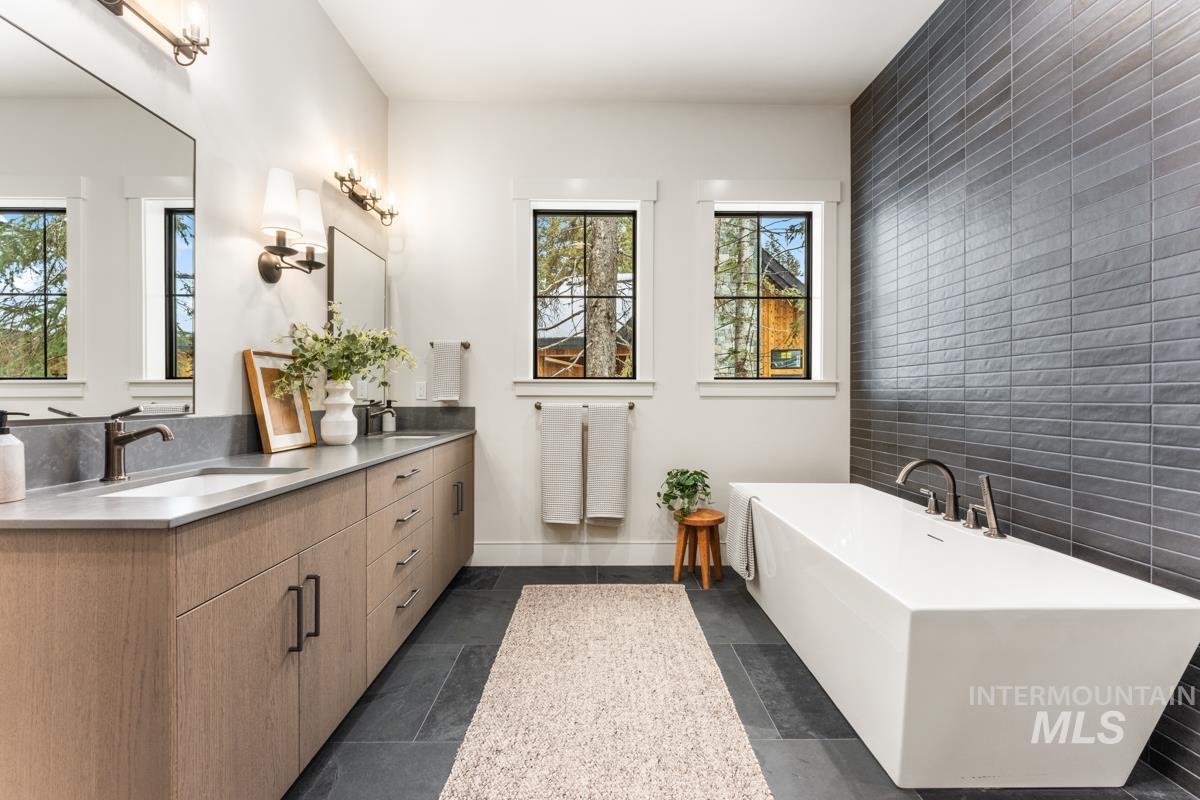 68 Ponderosa Ridge Donnelly, ID 83615 - Photo 4 of 29 Bathroom featuring double vanity, tile walls, a soaking tub, and stone tile floors