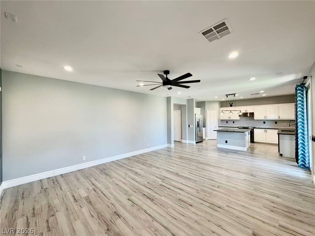 135 Tall Ruff Drive Las Vegas, NV 89148 - Photo 28 of 29 An open floorplan living area flows into a kitchen featuring an island and stainless steel appliances.