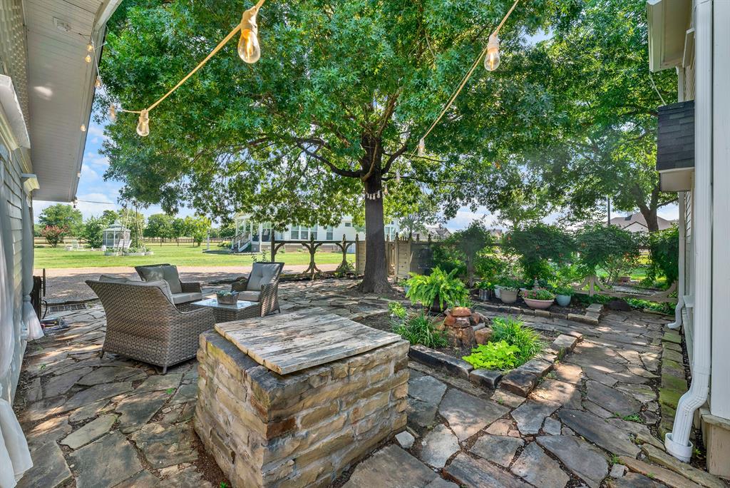 1425 Lone Star Road Celina, TX 75009 - Photo 23 of 40 Enjoy the inviting courtyard from another perspective, featuring beautiful stonework and established gardens. The expansive patio offers multiple gathering spaces, blending timeless character with relaxed outdoor living.