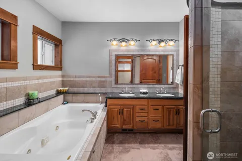 a bathroom with a tub a double vanity sink and a large mirror