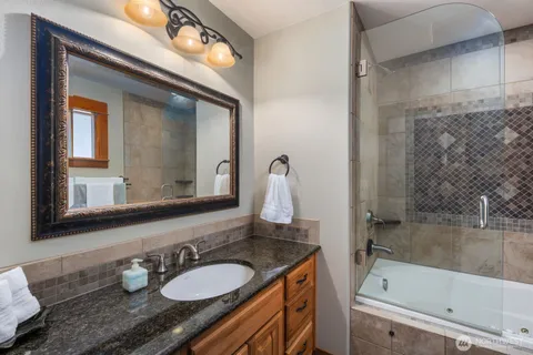 a bathroom with a granite countertop sink mirror vanity and bathtub