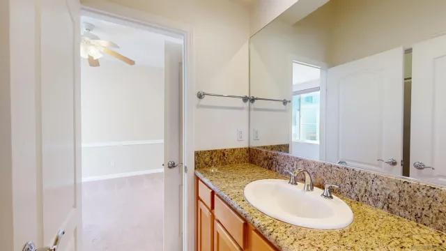 a bathroom with a granite countertop sink and a mirror