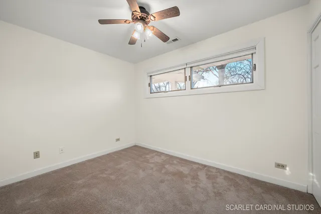 an empty room with a window and a ceiling fan
