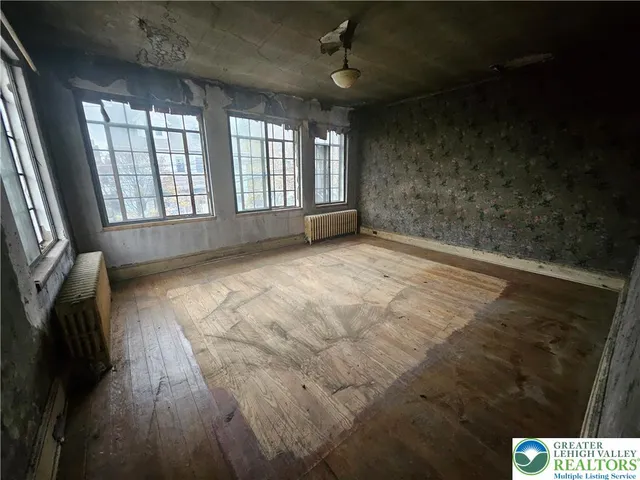 an empty room with wooden floor and windows