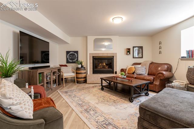 11170 Peaceful Valley Road Colorado Springs, CO 80925 - Photo 26 of 49 Living area featuring wood finished floors and a tiled fireplace