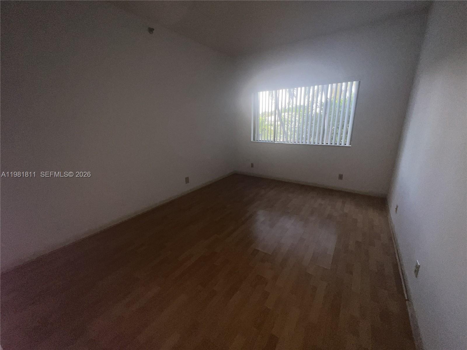 8816 Collins Avenue, Unit 105 Surfside, FL 33154 - Photo 20 of 30 a view of an empty room with wooden floor and a window