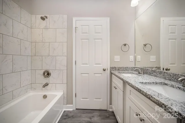 a bathroom with a granite countertop tub sink and mirror