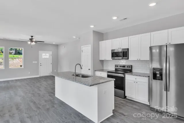 a kitchen with stainless steel appliances granite countertop a sink stove refrigerator and cabinets
