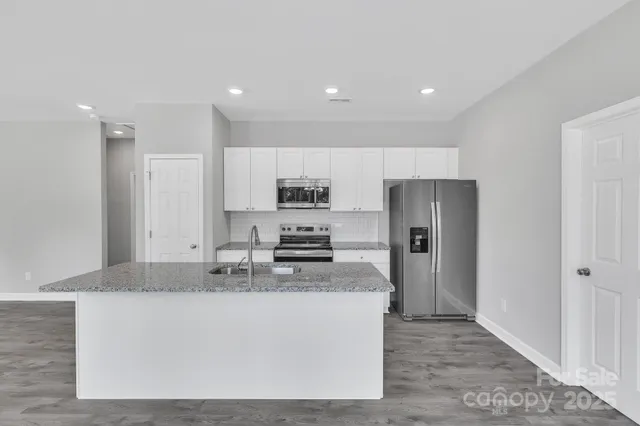 a kitchen with stainless steel appliances granite countertop a refrigerator a stove a sink and a granite counter tops