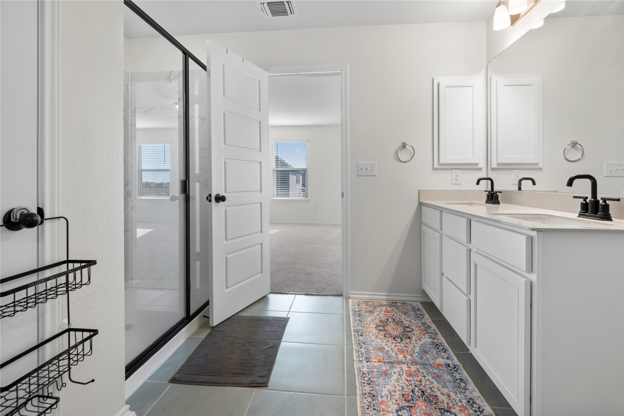 18501 Spotted Eagle Lane Elgin, TX 78621 - Photo 26 of 40 Full bath with double vanity, a shower stall, light tile patterned floors, and light colored carpet