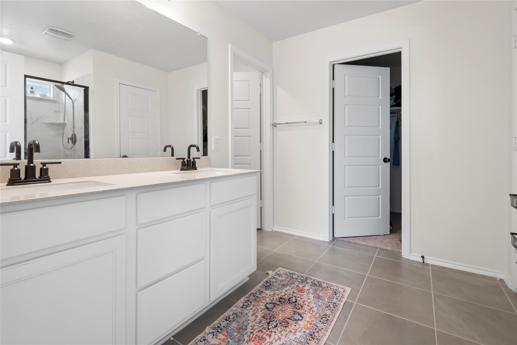 18501 Spotted Eagle Lane Elgin, TX 78621 - Photo 28 of 40 Bathroom featuring a shower stall, double vanity, light tile patterned floors, and a spacious closet