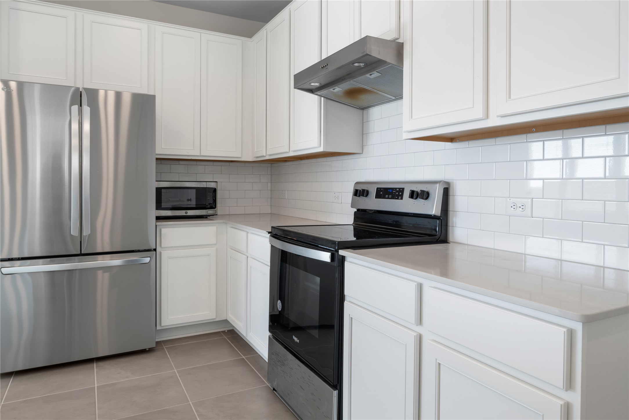18501 Spotted Eagle Lane Elgin, TX 78621 - Photo 9 of 40 Kitchen featuring stainless steel appliances, exhaust hood, and white cabinetry