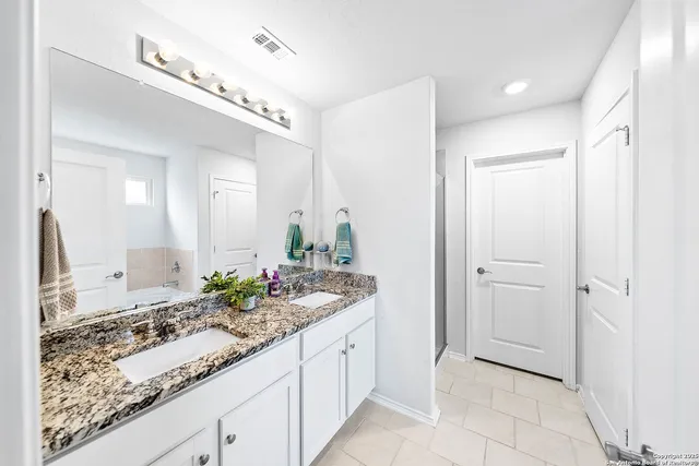 a spacious bathroom with a granite countertop sink and a mirror